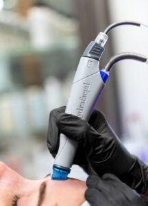 Esthetician performing a Hydrafacial treatment using a Hydrafacial handpiece on a woman’s face. 5 med spa treatments for low-maintenance beauty